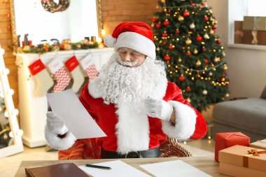 Noel Baba Noel için dekore edilmiş odada istek listesini okuyor.