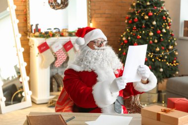 Noel Baba Noel için dekore edilmiş odada istek listesini okuyor.