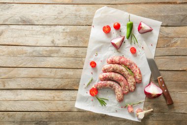 Ahşap arka plan üzerinde otlar, baharatlar ve sebzeler ile taze çiğ sosis