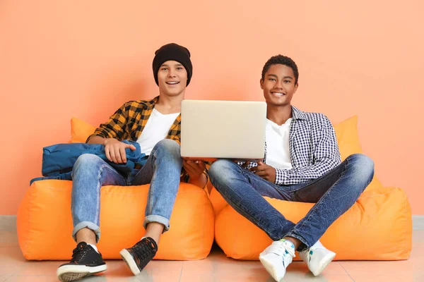 Retrato de jovens estudantes com laptop sentado perto da parede de cores — Fotografia de Stock