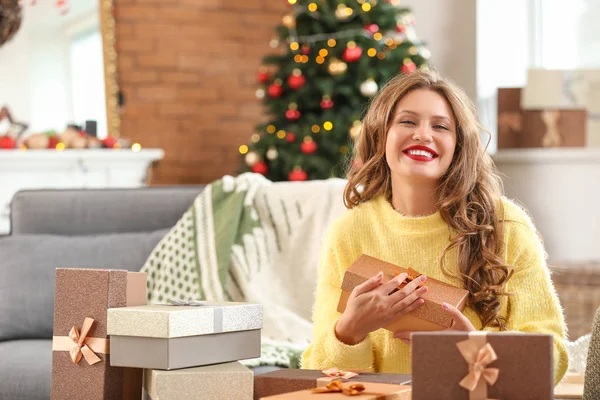 Happy young woman with Christmas gifts at home — Stock Photo, Image