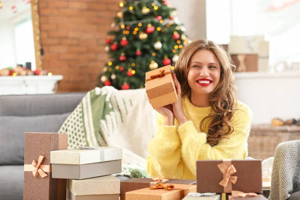 Happy young woman with Christmas gifts at home — Stock Photo, Image