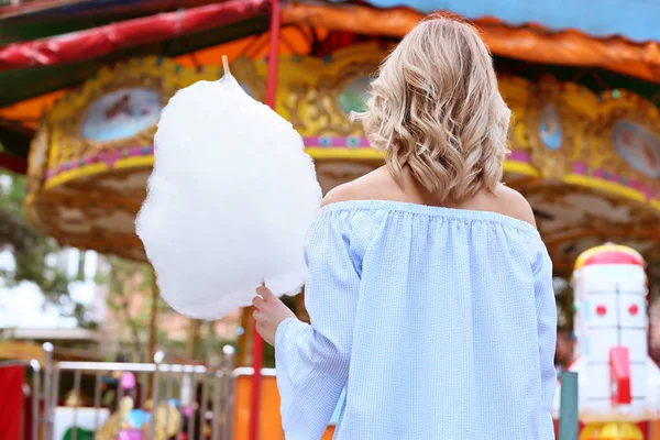 Woman with sweet cotton candy in amusement park, back view — Stock Photo, Image