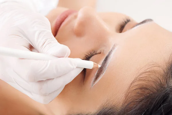 Jonge vrouw ondergaat wenkbrauw correctie procedure in schoonheidssalon, close-up — Stockfoto