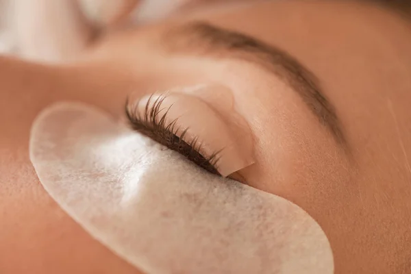 Young woman undergoing procedure of eyelashes lamination, closeup