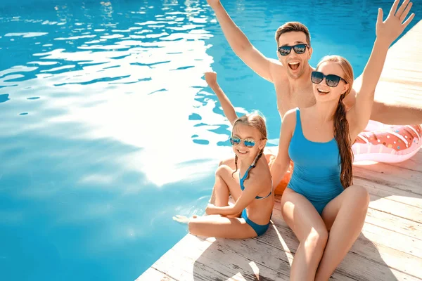 Happy family sitting near swimming pool — Stock Photo, Image