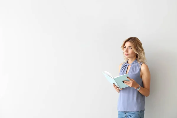 Retrato de mujer hermosa con libro sobre fondo claro — Foto de Stock