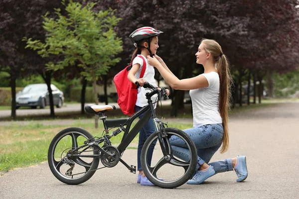 Μητέρα βοηθώντας την κόρη της να βάλει σε ποδήλατο κράνος σε εξωτερικούς χώρους — Φωτογραφία Αρχείου