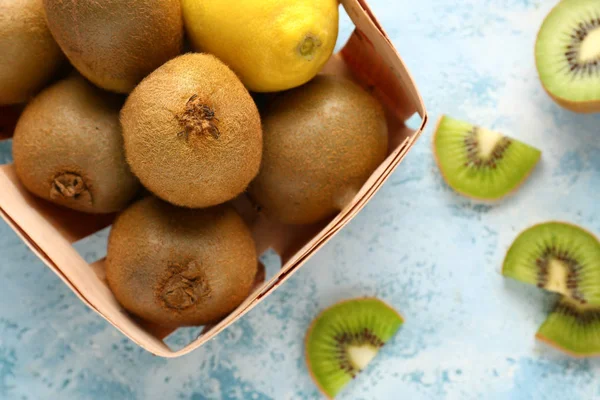 Tasty ripe kiwi and lemon in box on color background, closeup — Stock Photo, Image