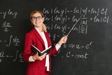 Sınıfta tahta yakın kitap ve işaretçi ile güzel matematik öğretmeni