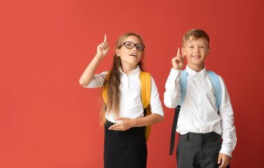 Renkli arka planda işaret parmakları yükseltilmiş küçük öğrenciler