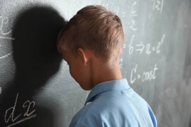 Kara tahta yakınında rahatsız küçük öğrenci