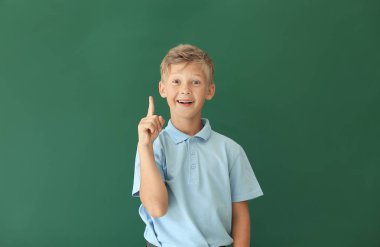 Renkli arka planda işaret parmağı olan küçük bir okul çocuğu.