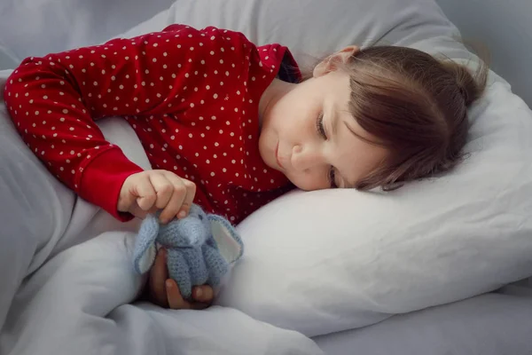 Cute little girl with toy lying in bed — Stock Photo, Image