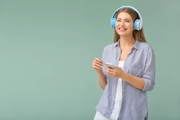 Young woman listening to audiobook on color background — Stock Photo, Image