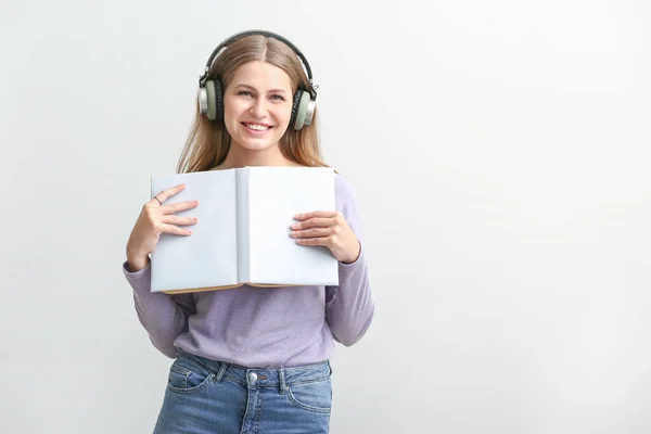 Junge Frau hört Hörbuch auf weißem Hintergrund — Stockfoto