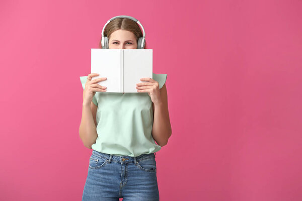 Young woman listening to audiobook on color background