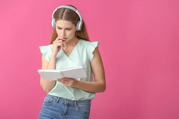 Mujer joven escuchando música y leyendo libro sobre fondo de color —  Fotos de Stock