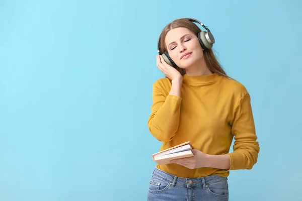 Young woman listening to audiobook on color background — Stock Photo, Image