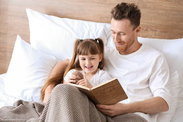 父亲和他的小女儿在床上看书 — 图库照片