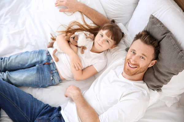 Porträtt av lycklig far och hans lilla dotter ligger på sängen, uppifrån — Stockfoto