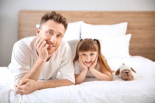 Porträtt av lycklig far och hans lilla dotter som ligger på sängen — Stockfoto