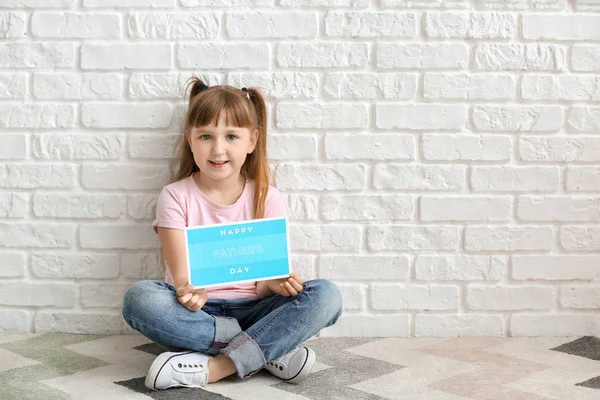 Симпатичні дівчинка з вітальну листівку на день батька сидять біля білої цегляної стіни — стокове фото
