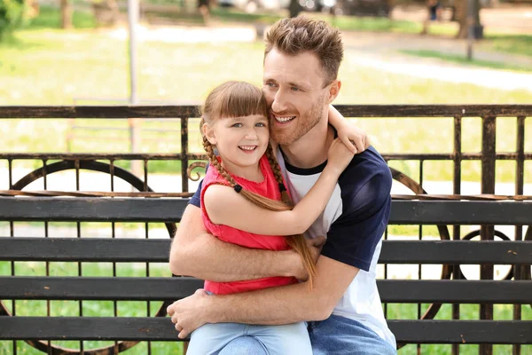 Portrait of happy father and his little daughter sitting on bench in park — Stock Photo, Image
