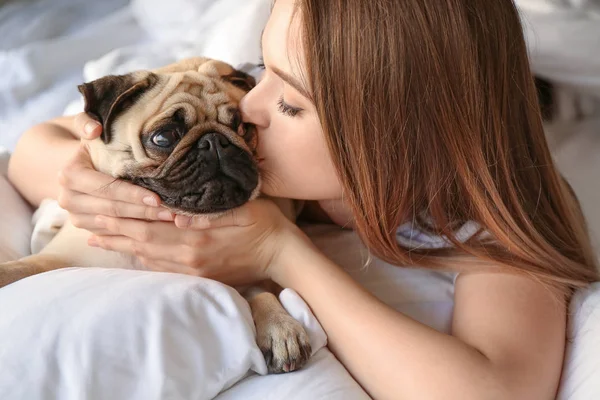 Mattina di bella giovane donna con simpatico cane carlino in camera da letto — Foto Stock