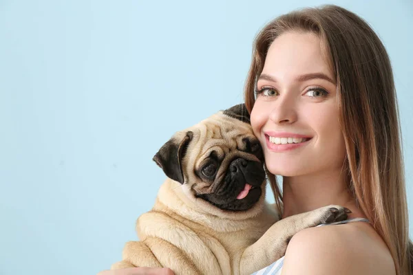 Beautiful young woman with cute pug dog on color background — Stock Photo, Image