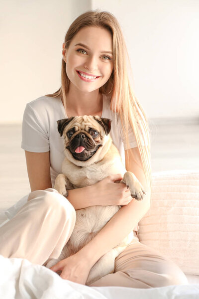 Красивая молодая женщина с милым мопсом дома

