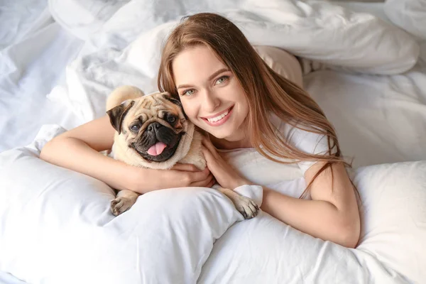 Morning of beautiful young woman with cute pug dog in bedroom — Stock Photo, Image