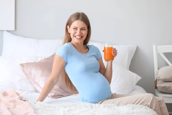 Krásná těhotná žena pije šťávu doma — Stock fotografie