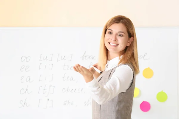 Beautiful English teacher calling out pupil during lesson in classroom — Stock Photo, Image