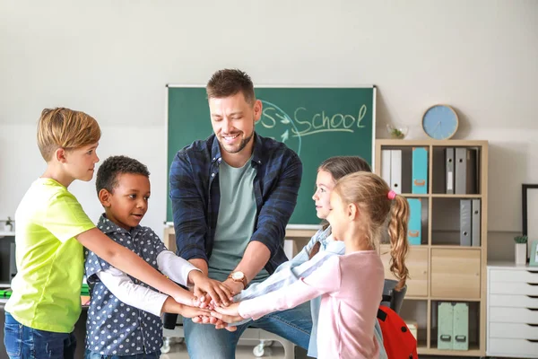 Crianças bonitos com professor dando as mãos juntos em sala de aula — Fotografia de Stock