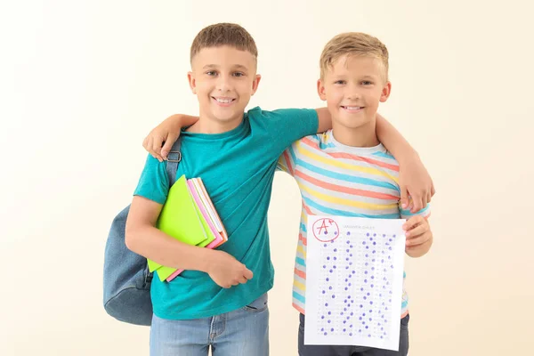 Meninos felizes com folha de resposta para teste escolar em fundo claro — Fotografia de Stock