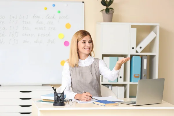 Mooie Engelse leraar die de leerling belt tijdens de les in het klaslokaal — Stockfoto