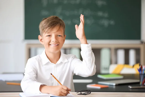 Pequeno aluno bonito levantando a mão durante a aula — Fotografia de Stock