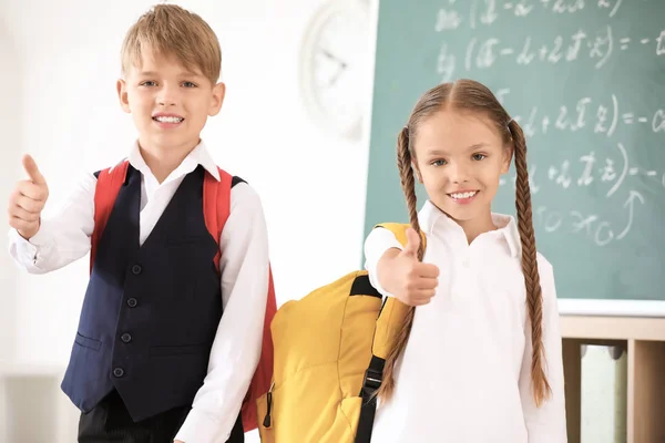 Niedliche kleine Schüler zeigen Daumen nach oben im Klassenzimmer — Stockfoto