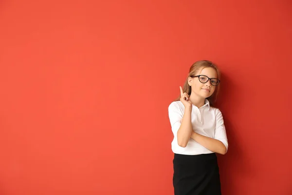 Little schoolgirl with raised index finger on color background — Stock Photo, Image