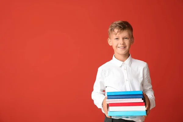 Kleiner Schuljunge mit Büchern auf farbigem Hintergrund — Stockfoto