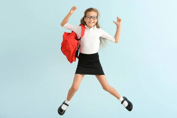 Jumping little schoolgirl on color background — Stock Photo, Image