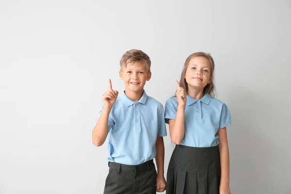 Kis tanulói emelt mutatóujjaival, világos háttérrel — Stock Fotó