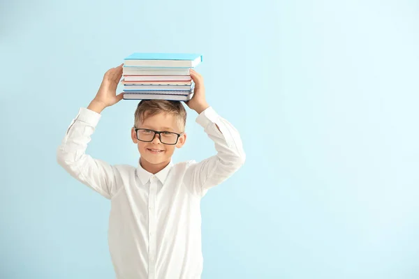 Kleiner Schuljunge mit Büchern auf farbigem Hintergrund — Stockfoto