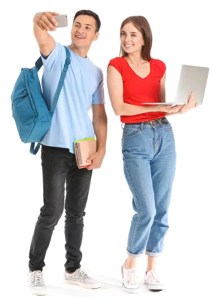 Retrato de jovens estudantes com laptop tirando selfie em fundo branco — Fotografia de Stock