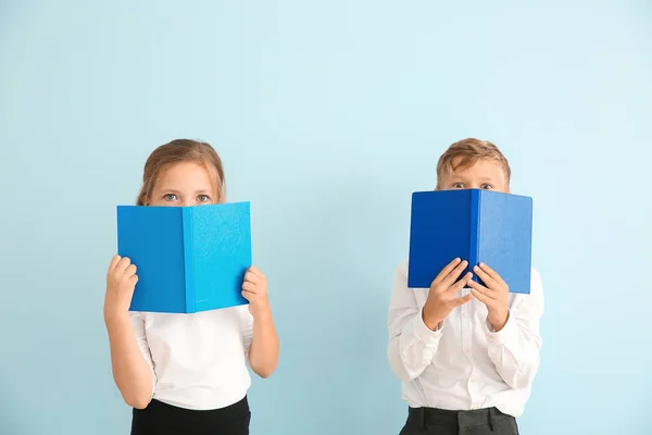 Little pupils with books on color background — Stock Photo, Image