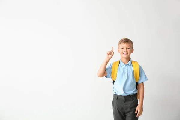 Маленький школяр з піднятим індексним пальцем на світлому фоні — стокове фото