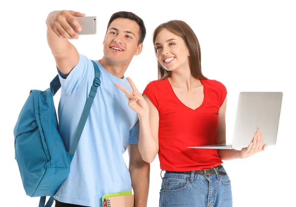 Portrait of young students with laptop taking selfie on white background — Stock Photo, Image