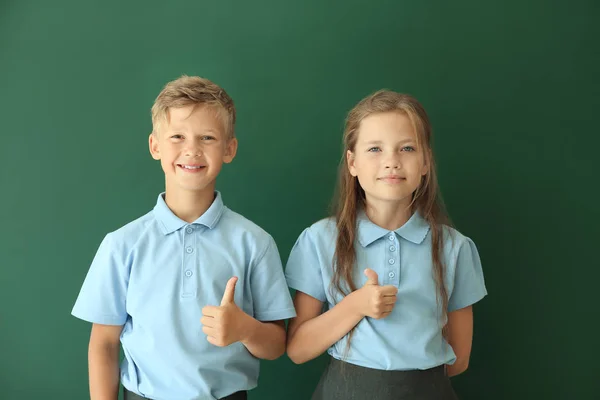 Little pupils showing thumb-up on color background — Stock Photo, Image