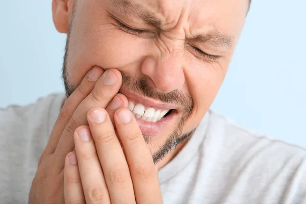 Man suffering from toothache against color background, closeup — Stock Photo, Image